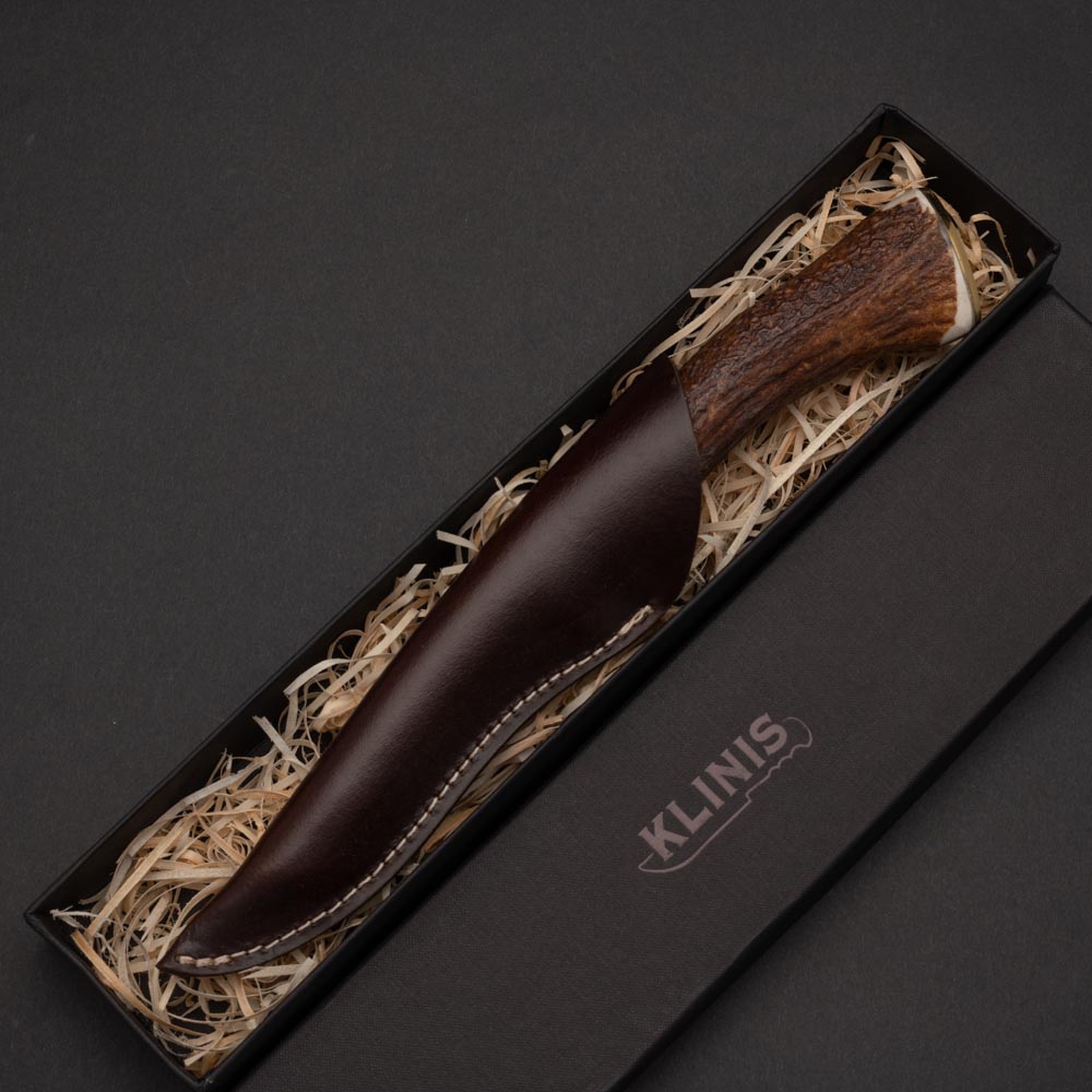 Κυνηγετικό μαχαίρι με λάμα από δαμασκηνό ατσάλι μπρούτζινο χειροφυλακτήρα και λαβή από και ολόκληρο κέρατο ελαφιού σε δερμάτινη θήκη μέσα σε χάρτινη κασετίνα